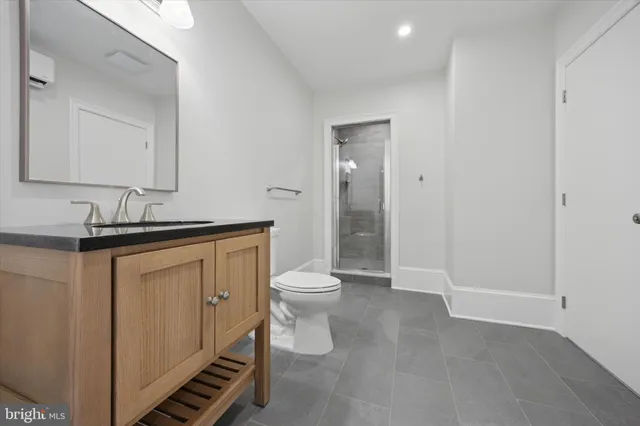 a bathroom with a granite countertop toilet a sink and a mirror