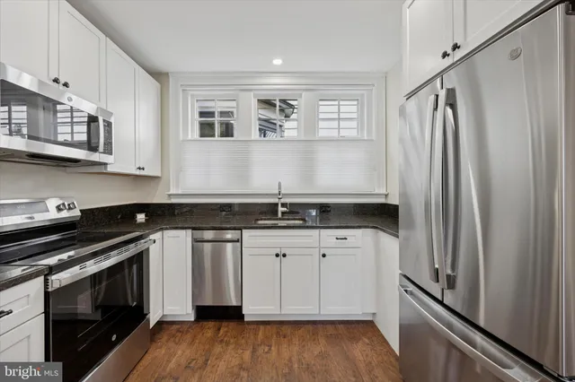 a kitchen with granite countertop a sink stove and refrigerator