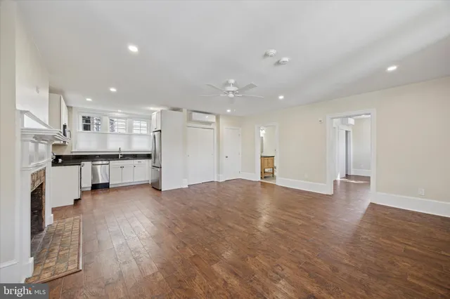 an empty room with wooden floor and kitchen view