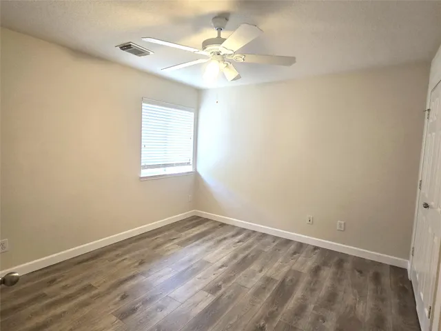 an empty room with a window and a fan