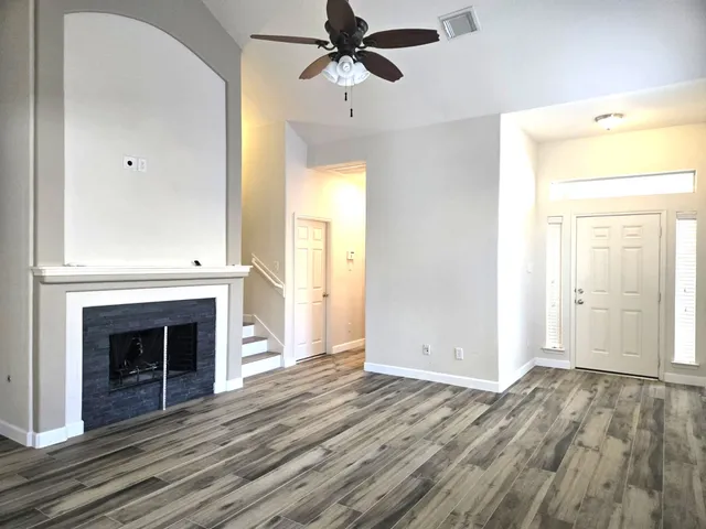 an empty room with wooden floor a ceiling fan and a fireplace