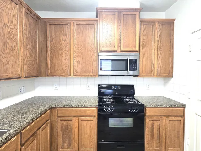 a kitchen with granite countertop cabinets stainless steel appliances and a counter space