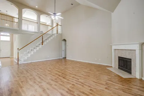 a view of an empty room with wooden floor a fireplace and a window