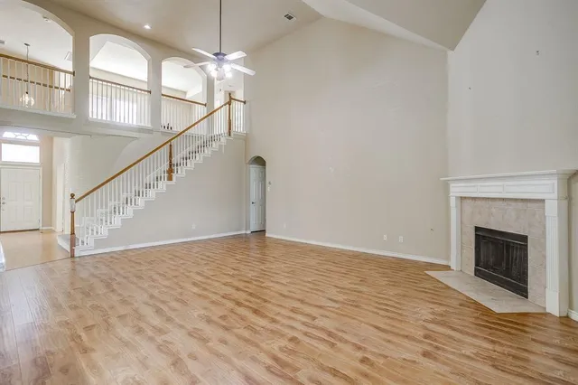 a view of an empty room with wooden floor a fireplace and a window