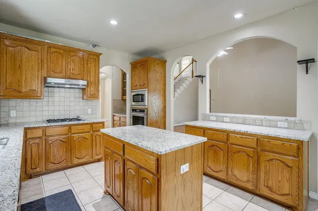a kitchen with granite countertop a sink stove and cabinets