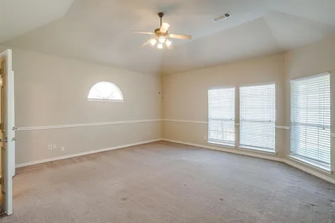 an empty room with windows and chandelier fan