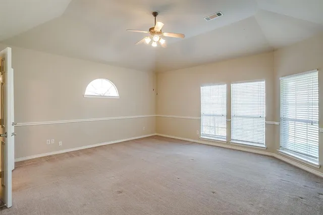 an empty room with windows and chandelier fan