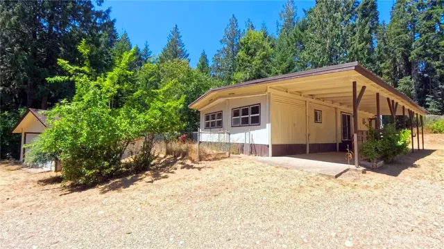 a view of house with yard and trees in the background