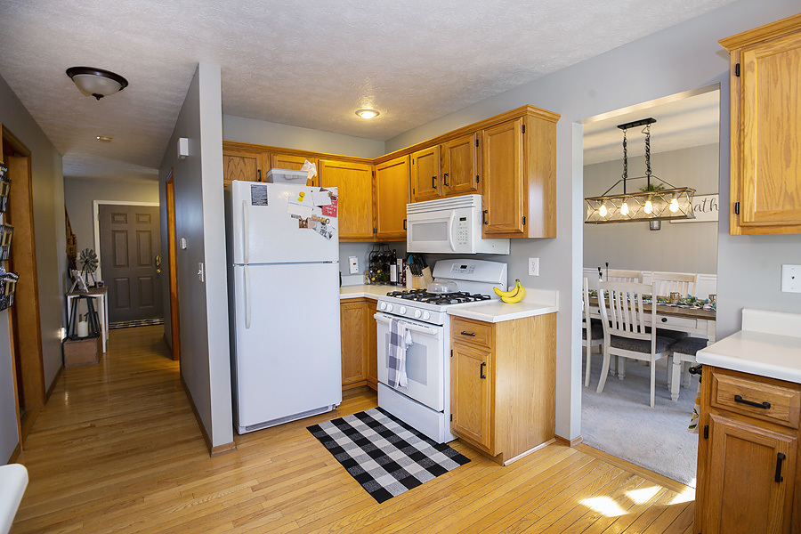 709 Landau Lane Normal, IL 61761 - Photo 20 of 44 a kitchen with refrigerator a stove a sink and a dining table with wooden floor