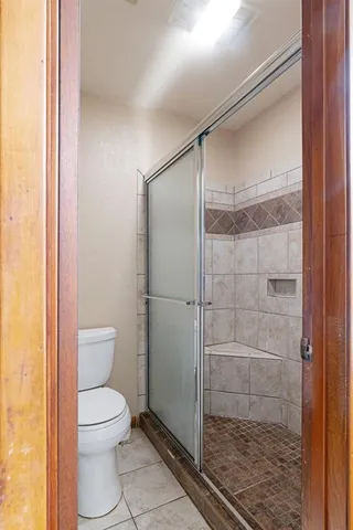 a bathroom with a toilet and a glass door shower