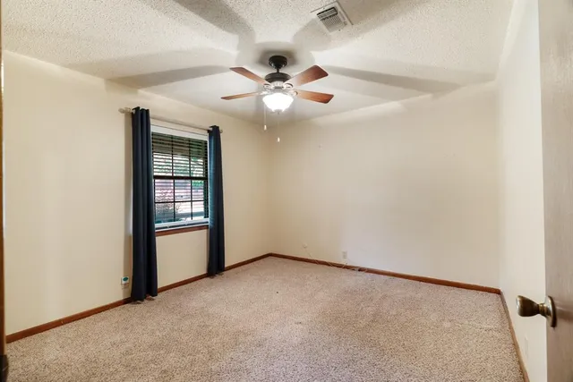 an empty room with windows and fan