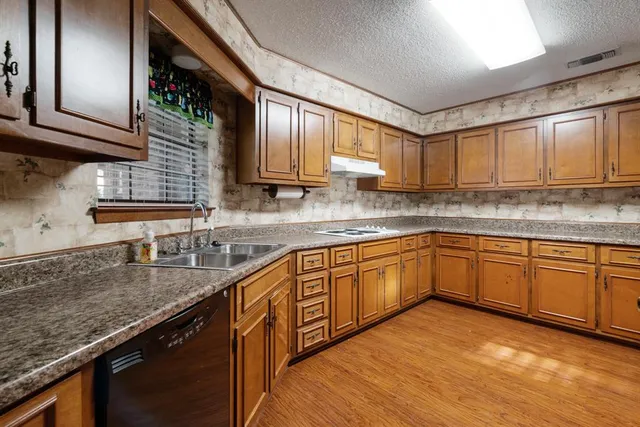 a kitchen with stainless steel appliances granite countertop wooden cabinets a sink and dishwasher