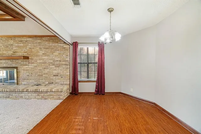 a view of empty room with wooden floor and chandelier