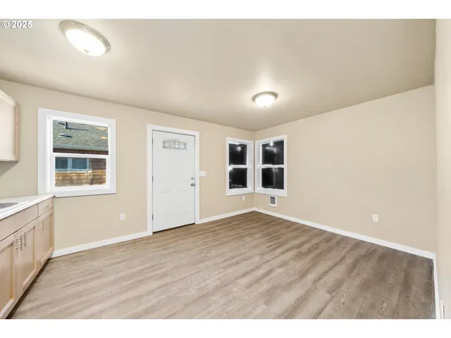 an empty room with wooden floor and windows