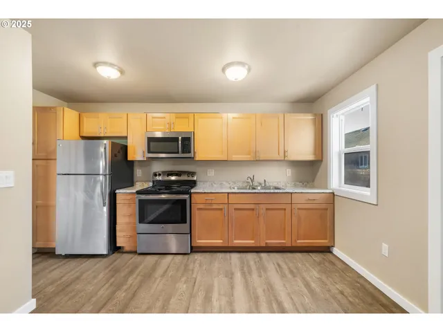 a kitchen with granite countertop wooden floors stainless steel appliances and window