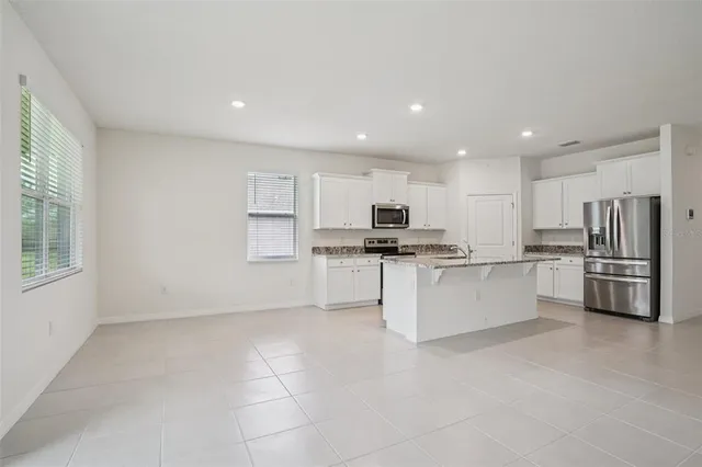 a large kitchen with white cabinets and stainless steel appliances