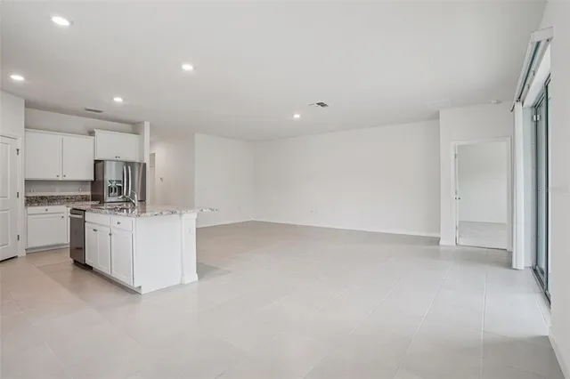 a kitchen with stainless steel appliances granite countertop a sink stove refrigerator and white cabinets with wooden floor