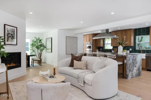 a living room with furniture and a fireplace with kitchen view
