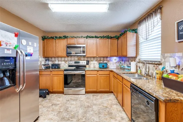 a kitchen with stainless steel appliances granite countertop a sink dishwasher stove and refrigerator