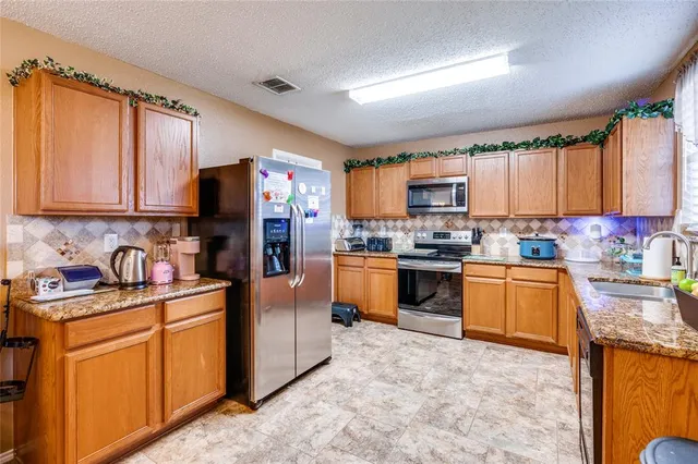 a kitchen with granite countertop stainless steel appliances a sink a counter top space cabinets and a window