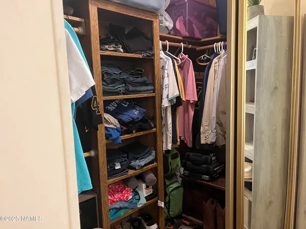 a view of walk in closet with clothes and shoes