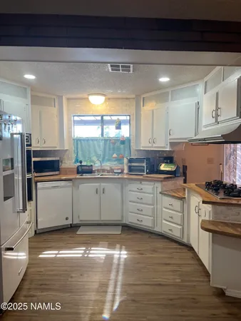 a kitchen with stainless steel appliances a stove a sink and white cabinets