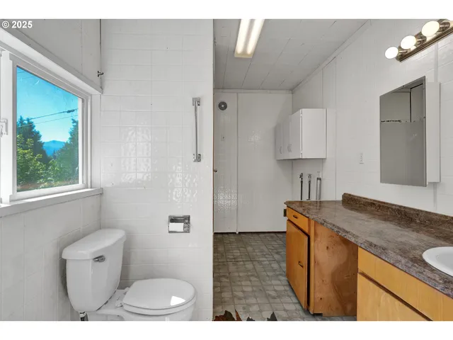 a bathroom with a granite countertop sink a toilet a mirror and shower