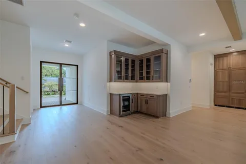 a view of an empty room with a window and kitchen view