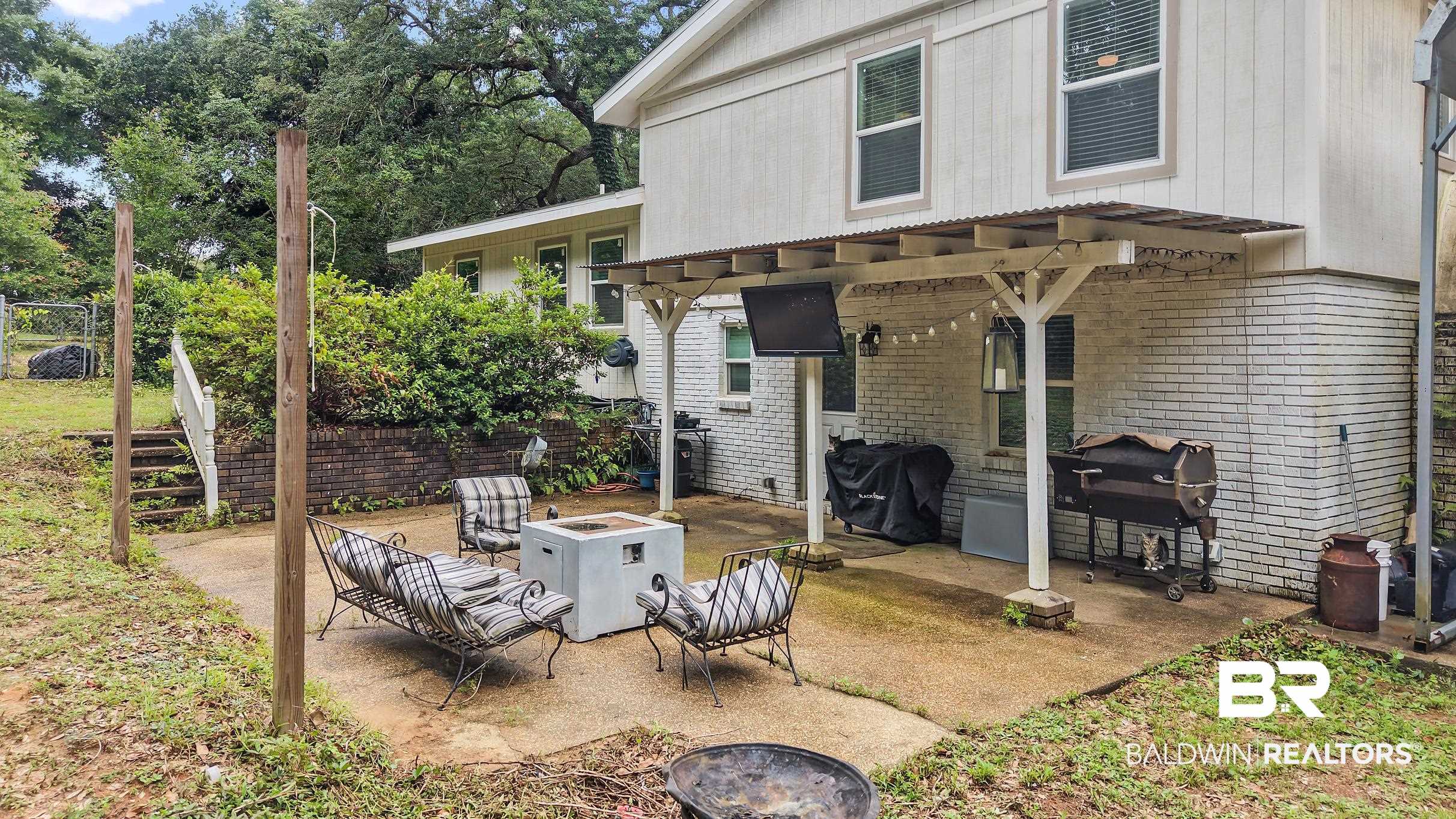 33129 Antietam Road Lillian, AL 36549 - Photo 25 of 31 Expansive concrete patio area featuring a white brick exterior and a corrugated metal roof overhang