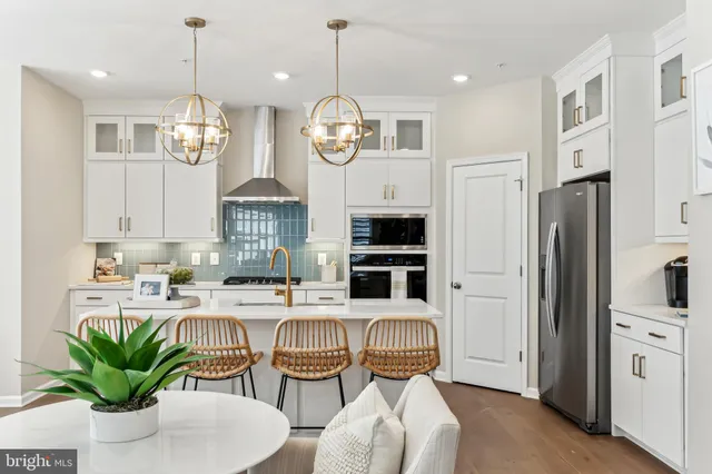 a kitchen with stainless steel appliances a dining table a stove a sink dishwasher a dining table and chairs with wooden floor