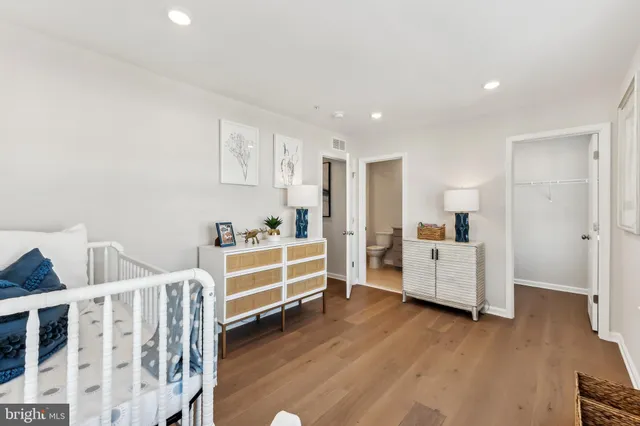 a bedroom with a bed and a dresser with wooden floor