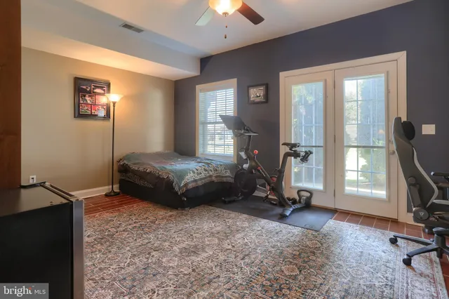 a bedroom with bed a desk and chair with window