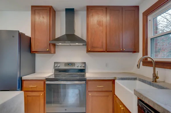 a kitchen with stainless steel appliances granite countertop a sink a stove and a refrigerator with wooden floor