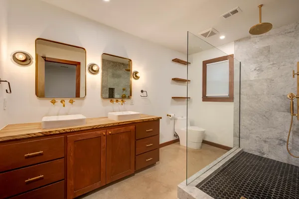 a spacious bathroom with a double vanity sink a mirror and a shower