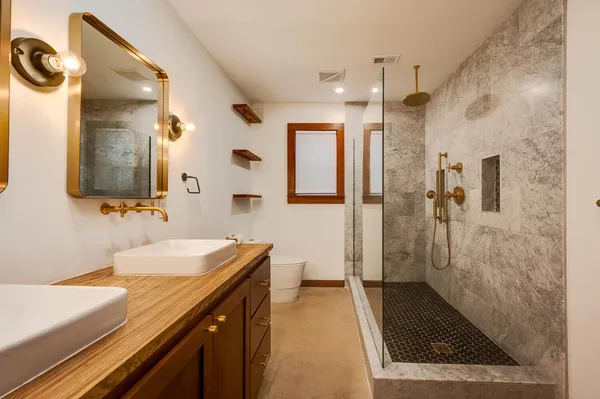 a bathroom with a sink a toilet a mirror and shower