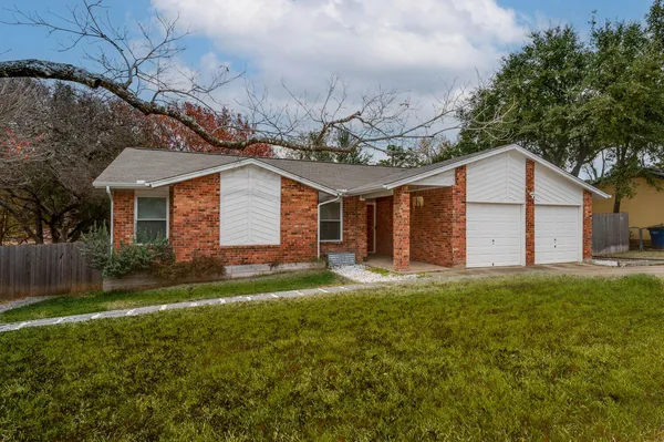 a view of a yard in front of a house with plants and large tree