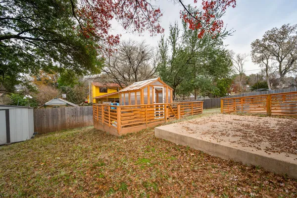 a view of a backyard with wooden fence and large trees