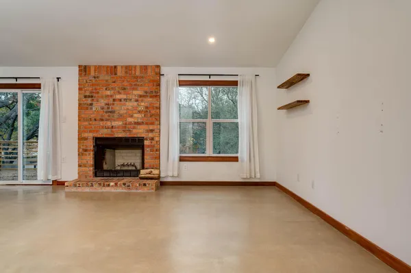 a view of an empty room with a fireplace and a window