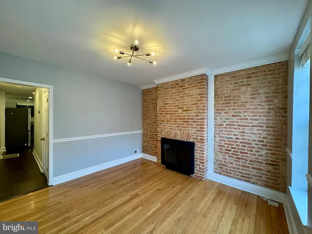 an empty room with wooden floor fireplace and windows