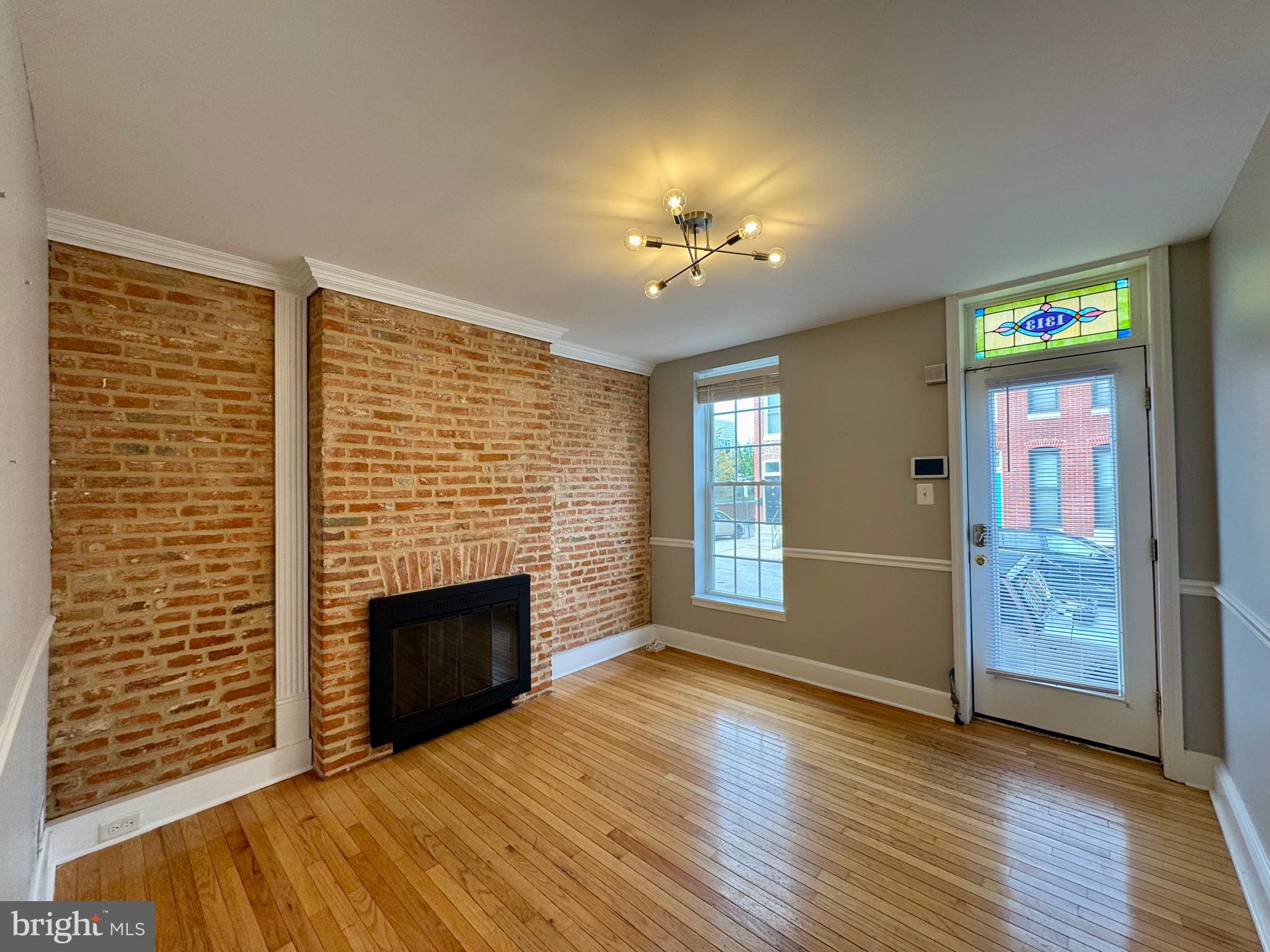1313 Patapsco Street Baltimore, MD 21230 - Photo 3 of 20 an empty room with wooden floor fireplace and windows