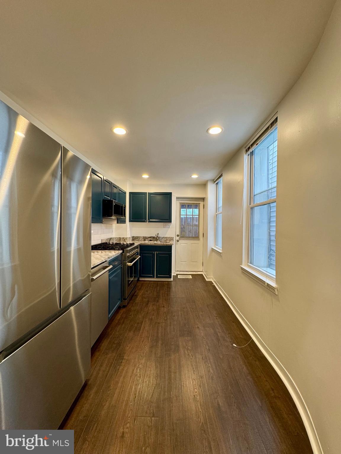 1313 Patapsco Street Baltimore, MD 21230 - Photo 5 of 20 a kitchen with stainless steel appliances kitchen island granite countertop a refrigerator a stove and a wooden floors