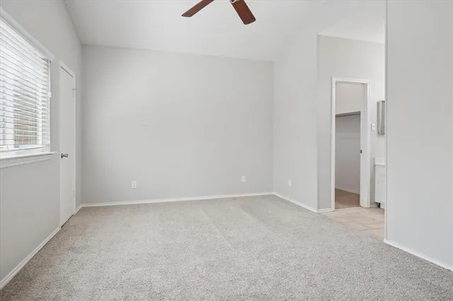 an empty room with a window and a ceiling fan