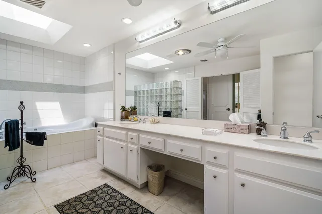 a spacious bathroom with a granite countertop sink a mirror and a bathtub