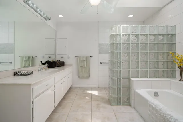 a large white bathroom with a double vanity sink a toilet a bathtub and shower