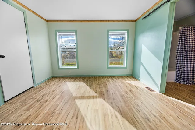 a view of an empty room with wooden floor and a window