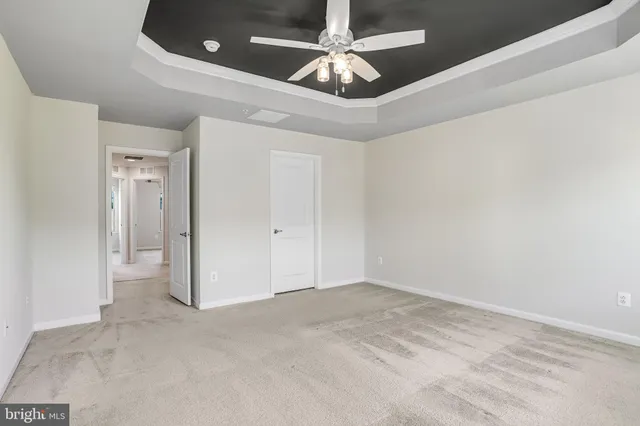 an empty room with chandelier fan and windows