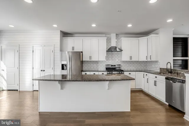 a kitchen with stainless steel appliances granite countertop a stove a sink and white cabinets