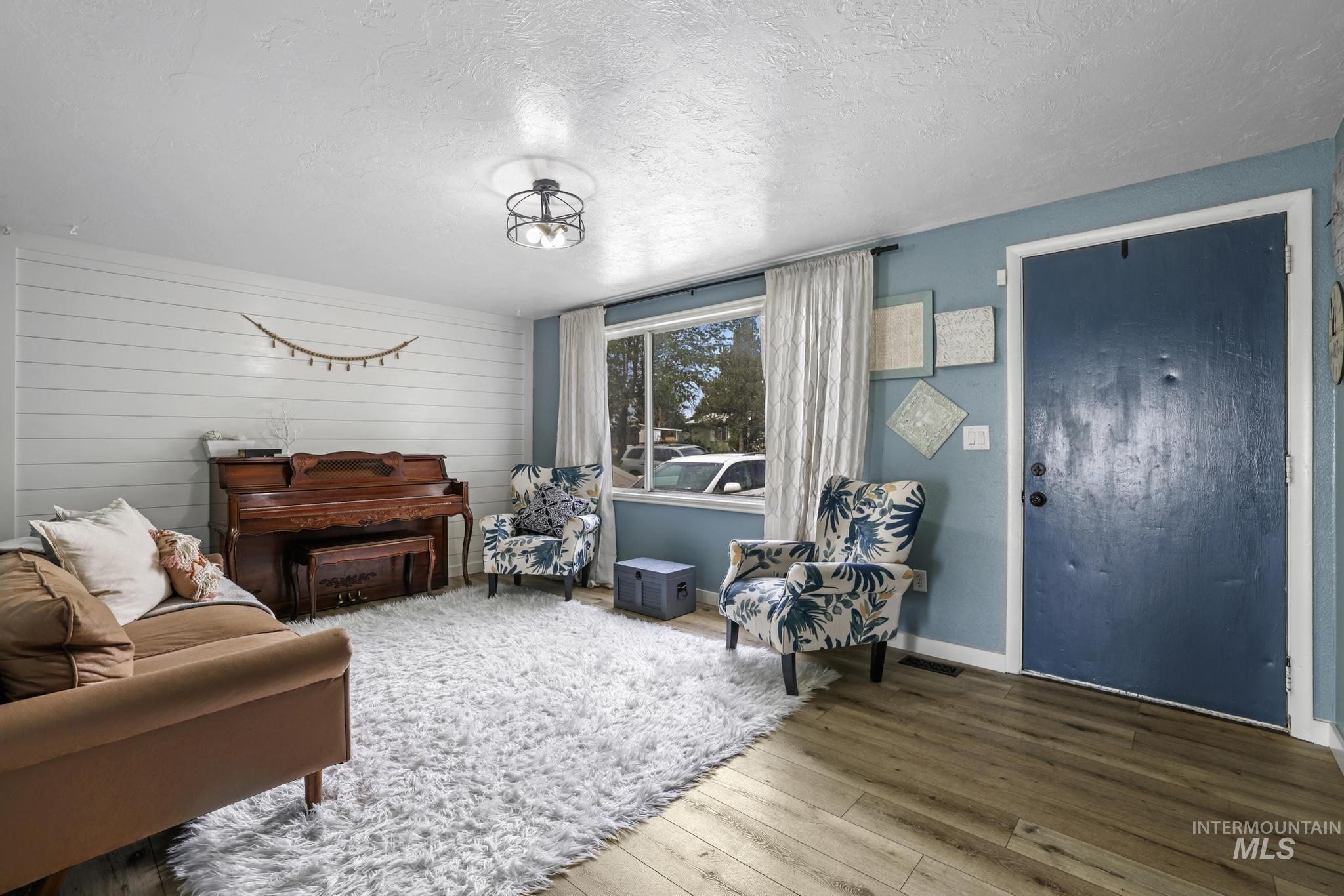 Living area featuring wood finished floors, a textured ceiling, and wooden walls