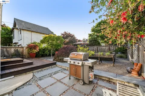 a view of a patio with a dining table and chairs under an umbrella with a barbeque