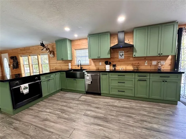 a kitchen with kitchen island granite countertop a sink a stove cabinets and wooden floor